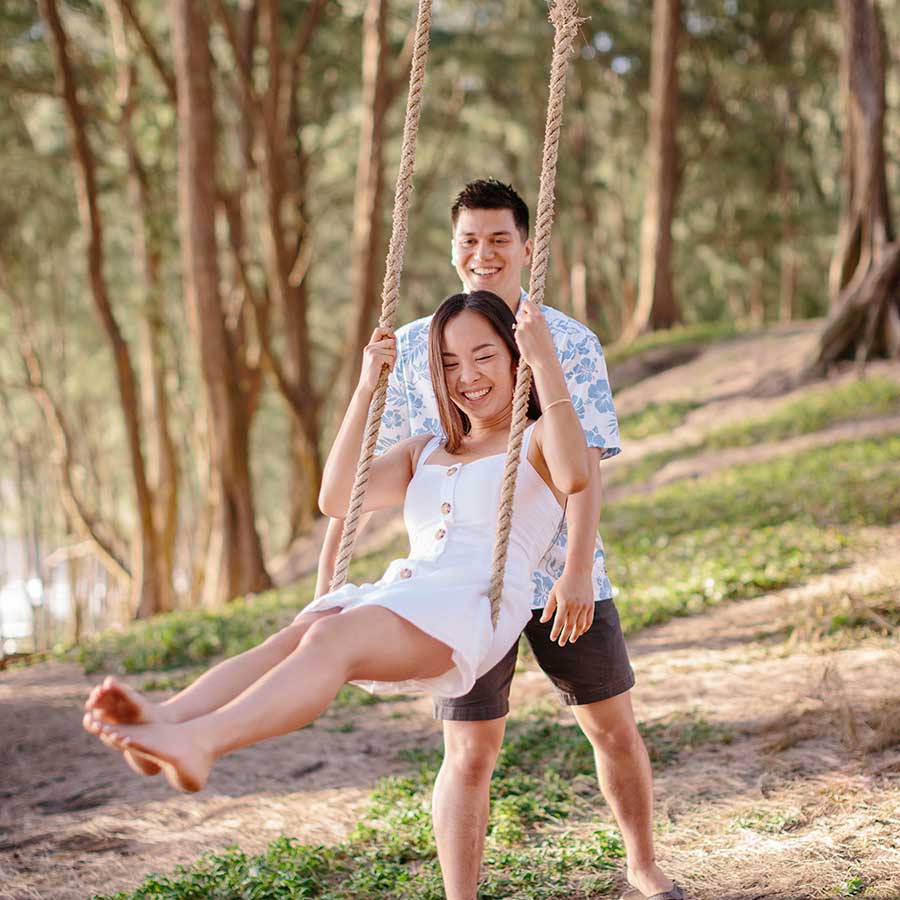 image of man swinging his girlfriend on a swing in the woods.